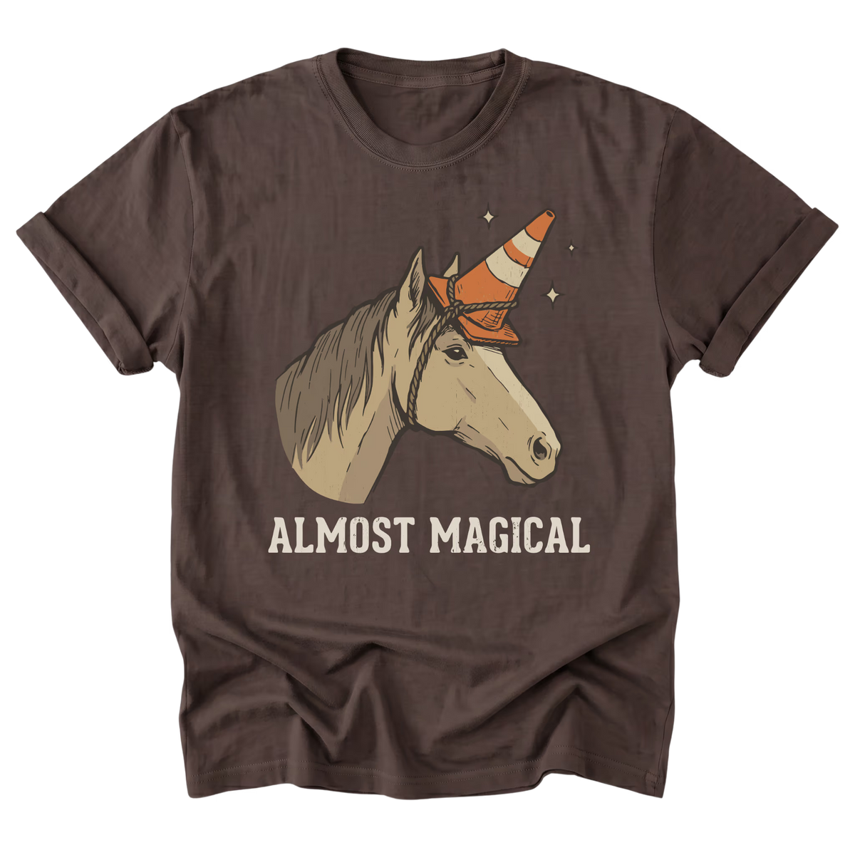 A dark brown short-sleeve t-shirt with a graphic of a beige horse wearing an orange and white traffic cone horn, with the text 'ALMOST MAGICAL' printed below in beige.