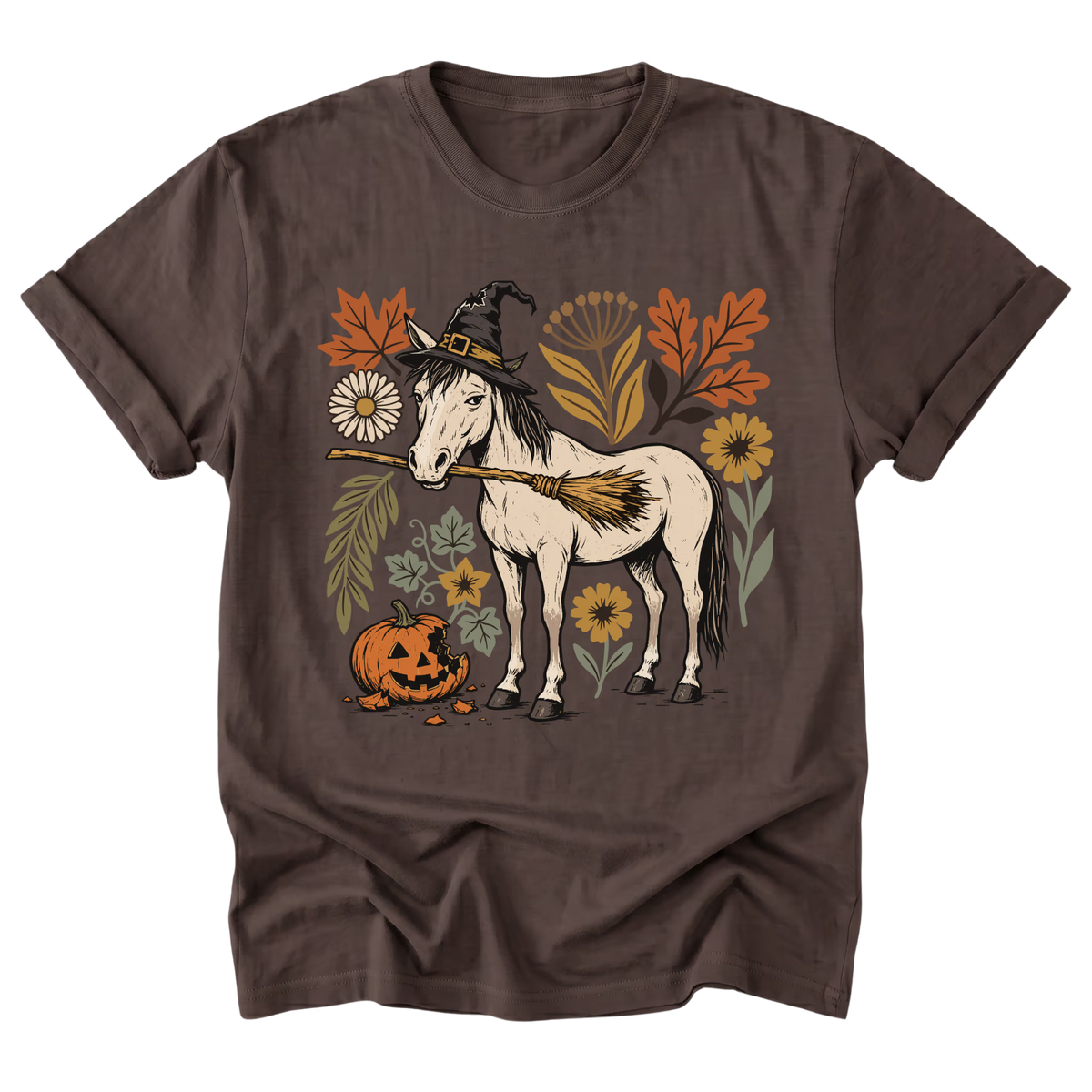 A dark brown short-sleeve crewneck t-shirt featuring a graphic of a white horse with a witch hat and broom, surrounded by autumn leaves, flowers, and a jack-o'-lantern pumpkin.
