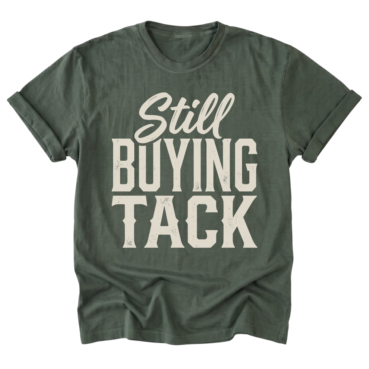 A military green t-shirt with a distressed off-white graphic text reading 'Still BUYING TACK' on the front, displayed against a solid white background.