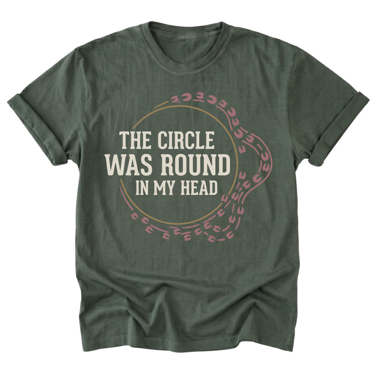 A military green short-sleeve t-shirt with a graphic print on the front. The graphic features the text 'THE CIRCLE WAS ROUND IN MY HEAD' in a beige serif font, surrounded by a circular gold line and pink footprints.