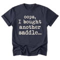 A navy blue short-sleeve t-shirt with rolled-up sleeves and a distressed white typewriter-style text print that reads 'oops, I bought another saddle.