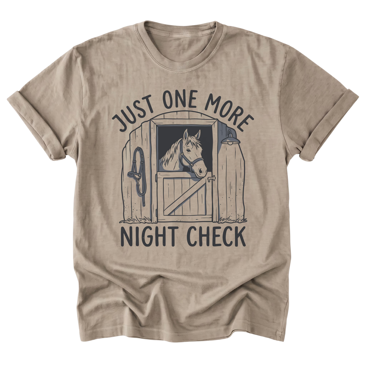 A sand beige crewneck t-shirt with a dark gray graphic of an horse in a stable doorway and the text 'JUST ONE MORE NIGHT CHECK'.