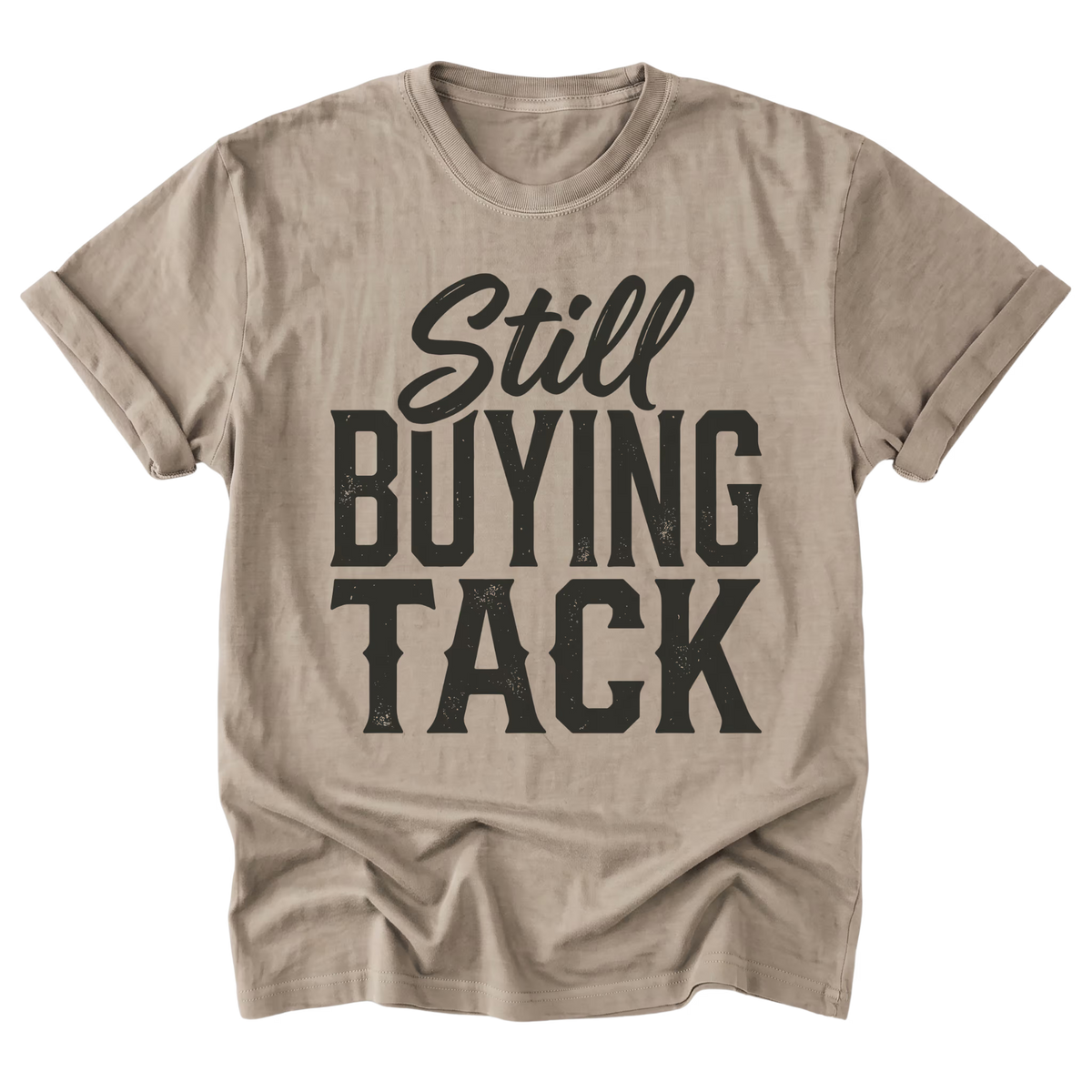A sand beige t-shirt with a distressed off-white graphic text reading 'Still BUYING TACK' on the front, displayed against a solid white background.