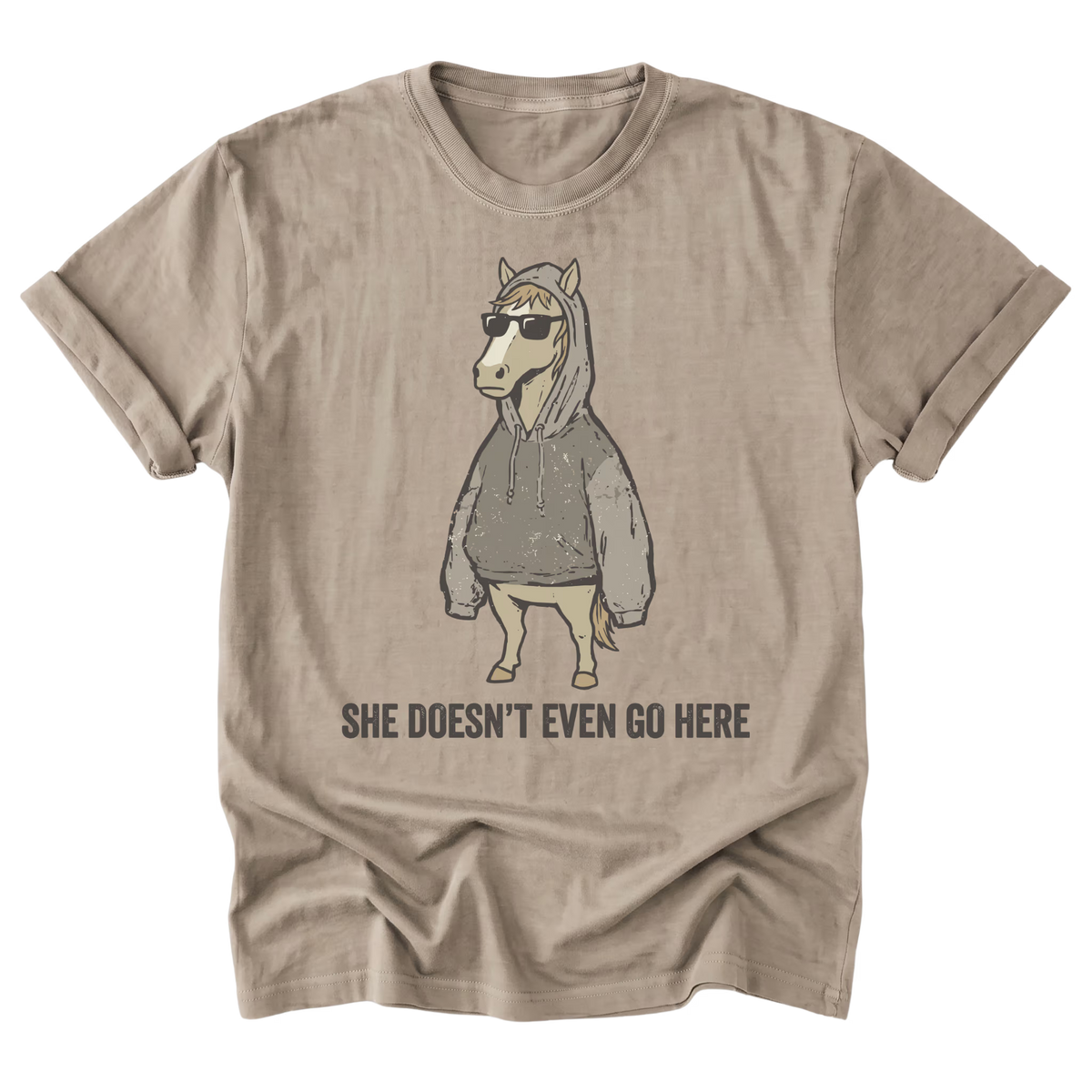 A sand beige graphic t-shirt of a horse wearing a hoodies and sunglasses with the text "She Doesn't Even Go Here" at the bottom